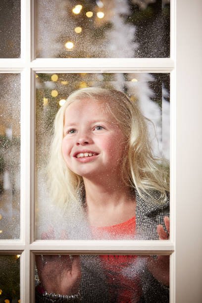 istock Girl looking through snowy window at Christmas. 876975628