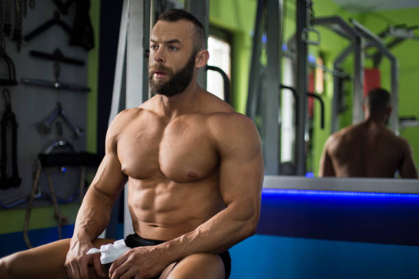 bodybuilder resting in the gym, drinks water - abdominal muscle extreme sports sensuality sex symbol imagens e fotografias de stock