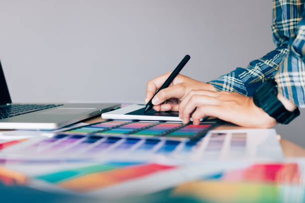 istock Freelance creative designers working on desk using digital graphic tablet and drawing with pen in modern home office. 876989902