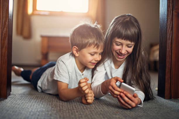 istock Brother and sister playing with smartphone 876995404