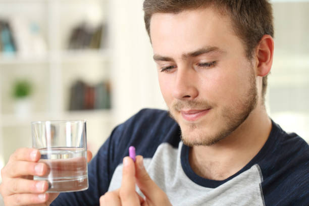 istock Serious man ready to take a pill on a couch 876998246