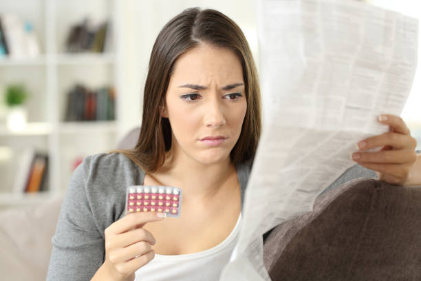 worried woman reading contraceptive pills leaflet - contraceção imagens e fotografias de stock