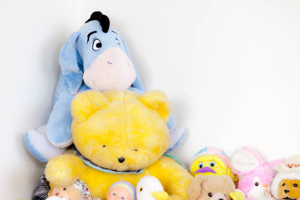 Many colorful peluches are all together near the wall of the room