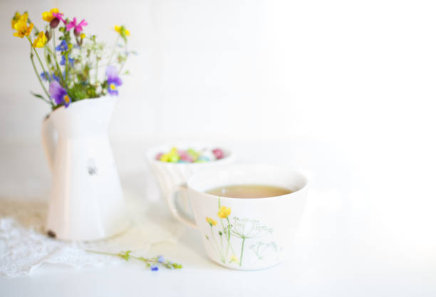 Cup of tea with meadow's flowers in vase stock photo