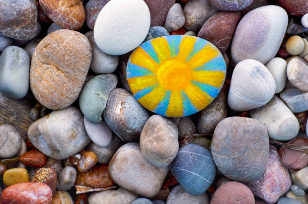 Bright sun painted on pebble. Pebbles background. stock photo