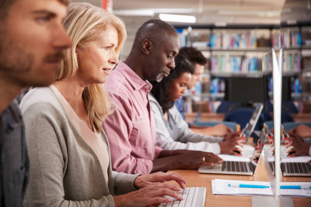 istock Group Of Mature College Students Working On Computers In Library 877024096