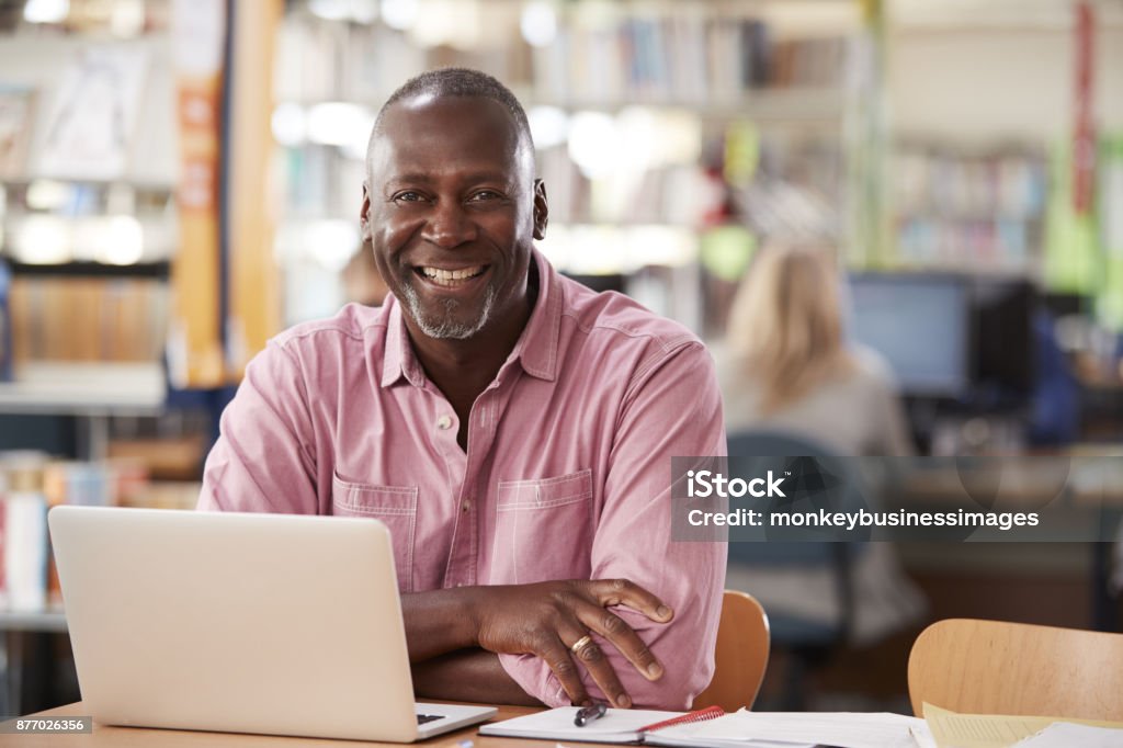 Portrait Of Mature Male Student Using Laptop In Library Men Stock Photo