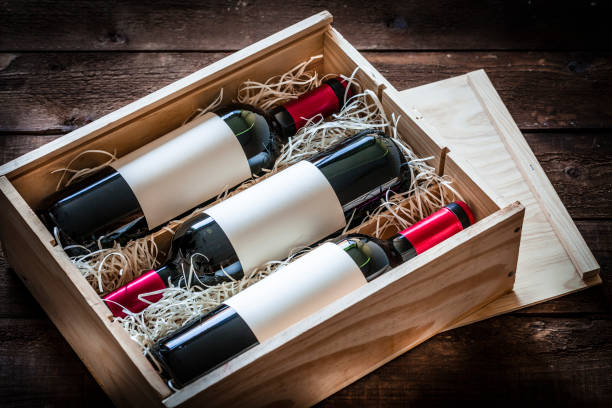 Red wine bottles packed in a wooden box shot rustic wooden table