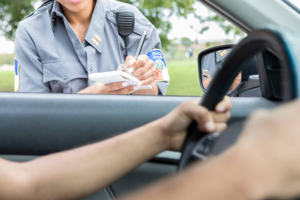 Unrecognizable police officer writes traffic violation ticket Unrecognizable female police officer writes a ticket to an unrecognizable male driver. The driver is holding on to the steering wheel. broken side view mirror stock pictures, royalty-free photos & images
