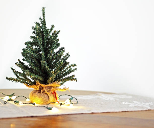 Mini Christmas tree with lights on seasonal table runner stock photo