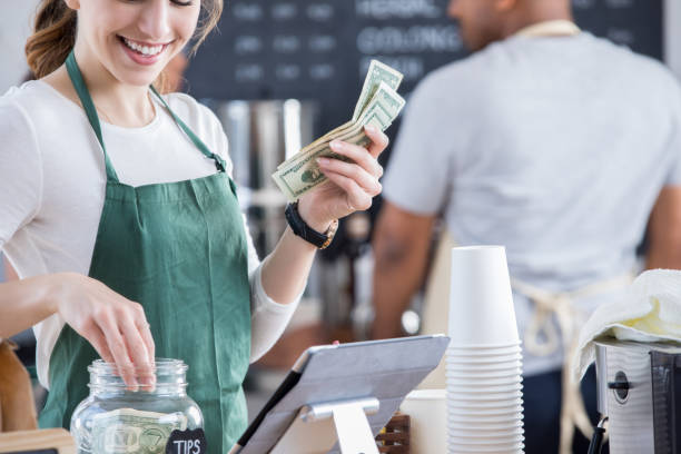 istock Smiling young female barista pulls money from tips jar 877030950