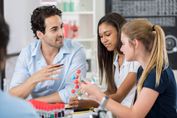 istock High school chemistry teacher talks with students during chemistry lab 877033892