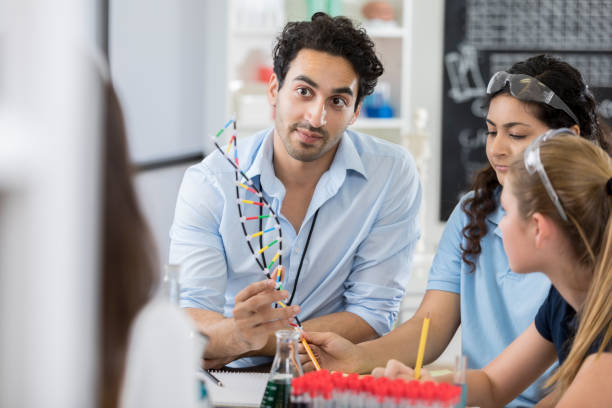 istock Handsome male science teacher works with students 877033936