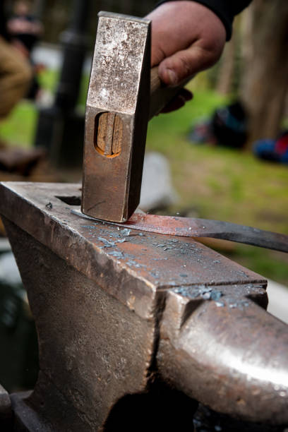 istock Master a man forges a sword from a red-hot metal on an anvil 877034110