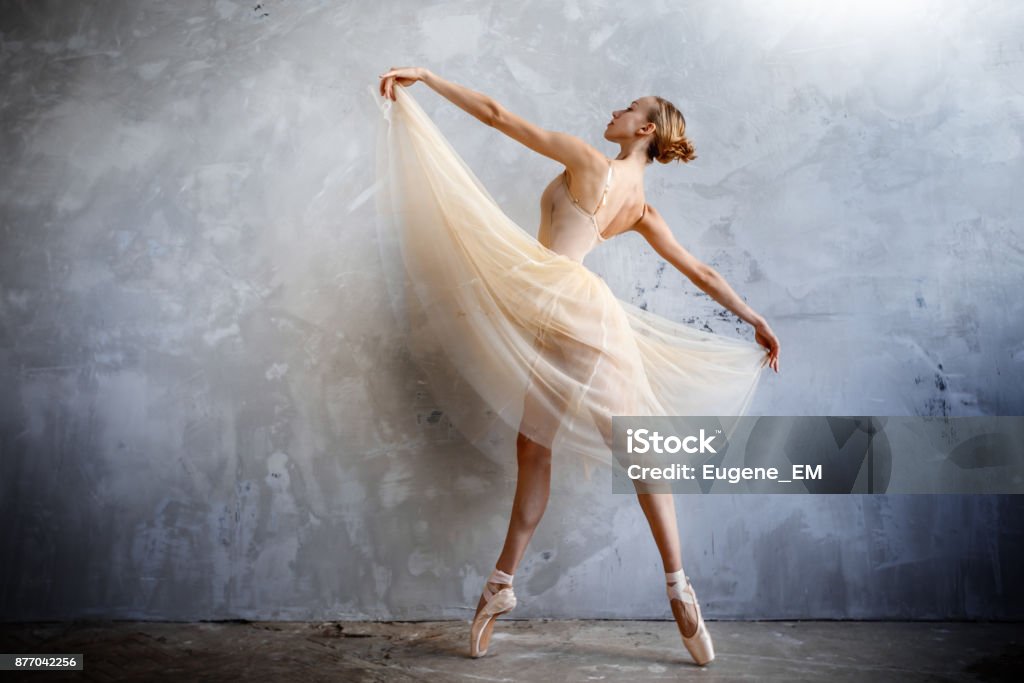 Young ballerina in a golden colored dancing costume is posing in a loft studio Young slim ballerina in a golden colored dancing costume is posing in a loft studio Ballet Dancer Stock Photo