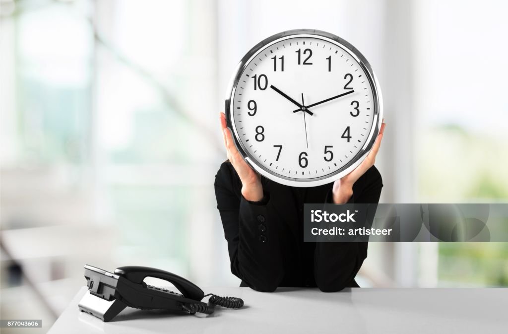 Working. Frustrated young businessman holding clock on background Adult Stock Photo