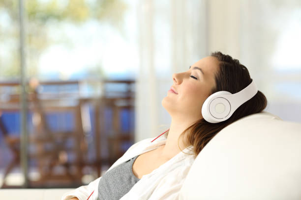 mujer relajarse escuchando música en un sofá - tourist resort audio fotografías e imágenes de stock