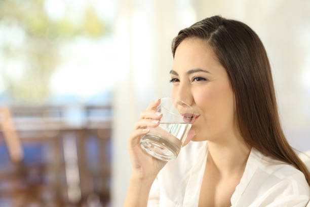 istock Woman drinking water in a glass at home 877053864
