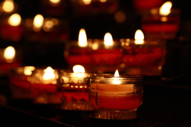 istock Red candles burning in dark church close up 877060998