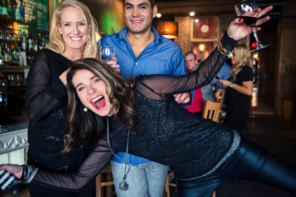 Woman photobombing in front of coworkers party in a bar. It’s the end of the year, a time to celebrate between friends and coworkers! Woman photobombing in front of couple of coworkers. Horizontal waist up indoors shot with copy space. This was shot in Quebec, Canada. photo bomb stock pictures, royalty-free photos & images