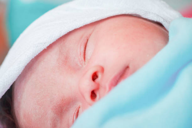 Newborn baby eyes closed sleeping in bed