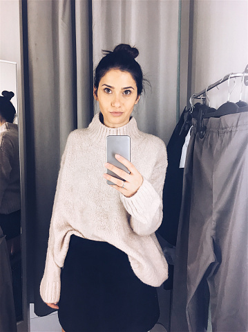 Young woman trying clothes in a fitting room and photographing herself in a mirror // mobile stock photo made with iPhone 6s