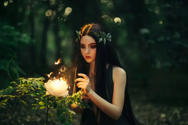 A fabulous, forest nymph with long hair found a flaming, fiery flower, with which little butterflies and fairies fly out. Artistic Photography
