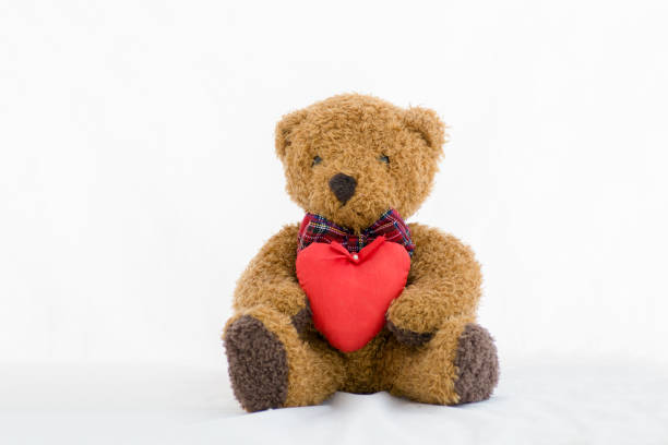 istock Brown teddy bear with red heart on a white background 877072432