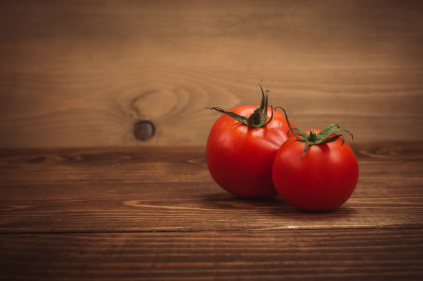 istock Two fresh organic tomatoes on rustic wooden table 877083122