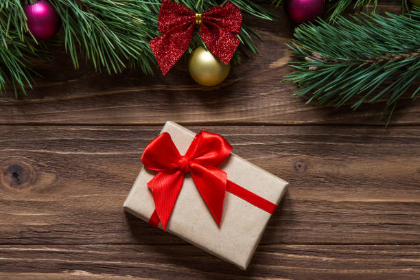 istock Nice Christmas gift box macro on the wooden background with pine tree branches on the top of the screen. 877083384