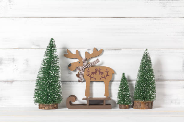 istock Wooden reindeers on sled with christmas tree on white wood over white rustic background with copy space for text 877083920
