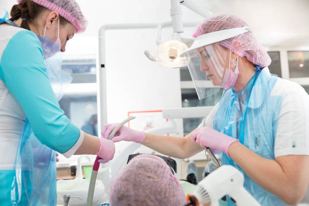 istock dentist takes  saliva ejector from nurse 877087154