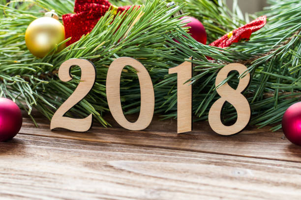 istock Extremely cute New Year 2018 macro, pine tree background with christmas balls and red bows on the wooden table 877087788