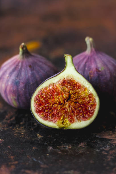 istock Half of fresh ripe figs on rusty metal surface. 877103028