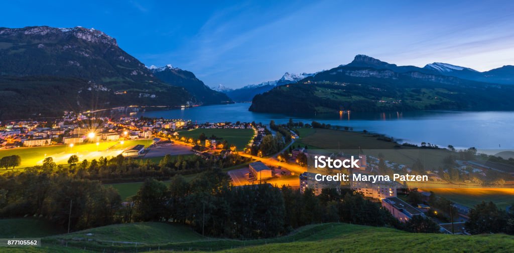 Night panorama of lake Lucerne. Brunnen. Canton Schwyz. Night panorama of Lake Lucerne. Mountain range, snow on the tops of the mountains. Axenstrasse. Lights in the houses and along the road.  Switzerland, Alps. City Stock Photo