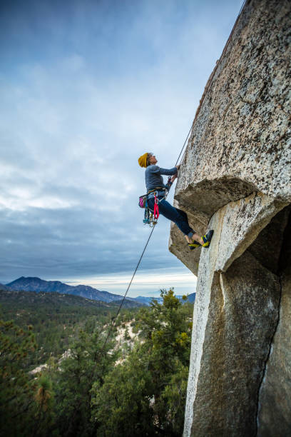 istock Profile Shot of Rock Climber Navigating Overhang 877106162
