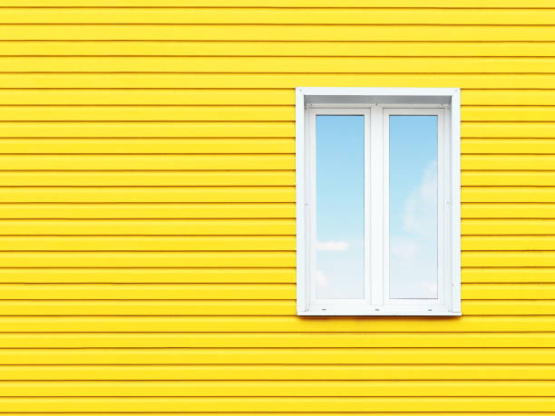 istock White plastic window on the wall of yellow siding. Photo with space for text. 877109300