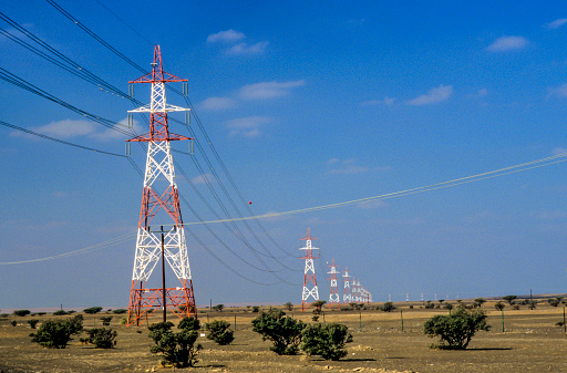 electric pylon row by row under blue sky in the desert of Oman