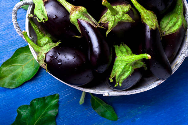 istock Fresh eggplant in grey basket on blue wooden table.Rustic background. Top view. Copy space. Vegan vegetable. 877117940