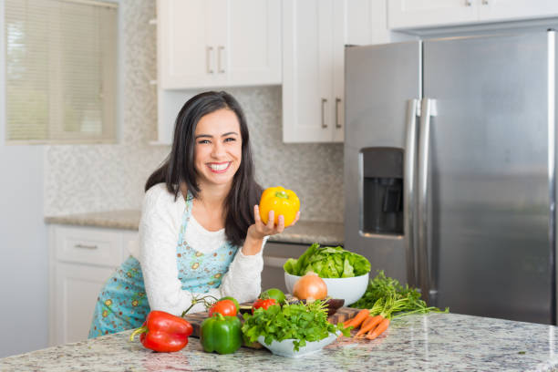 istock Young Hispanic Women Preparing a Meal Holding A Bell Pepper 877125464