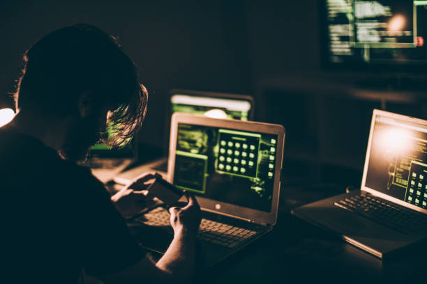 istock Hacker holding credit card in front of the computer 877132742