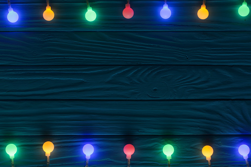 christmas garland lights on blue wooden background with copy space for your text. Top view.