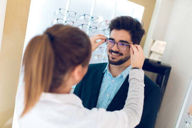 istock Young man selecting eyeglasses in optical shop 877148324