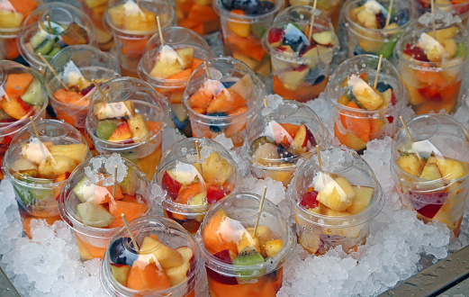 very fresh fruit salad with pieces of fruit and ice cubes for sale at vegan bar
