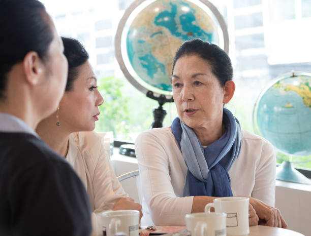 istock Three older Japanese women (teachers?)  in cafe, seen through window 877152560