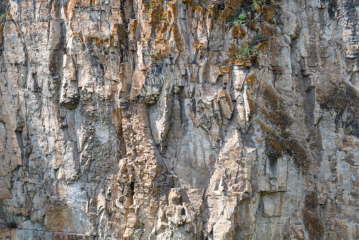 Detail closeup of a mountain rock wall, background or wallpaper of natural stone texture.
