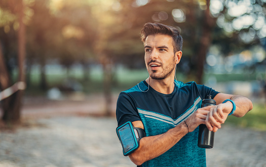 Attractive sportsman using a smart watch in the park.