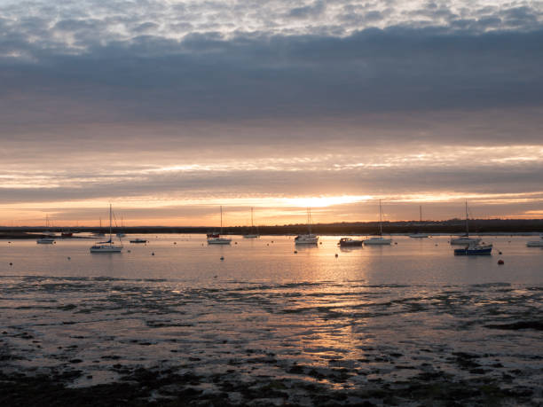 istock sun set sky dramatic clouds sea front beach harbor marina boats moored landscape 877184064