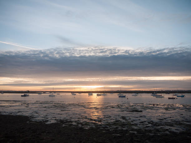 istock sun set sky dramatic clouds sea front beach harbor marina boats moored landscape 877184072