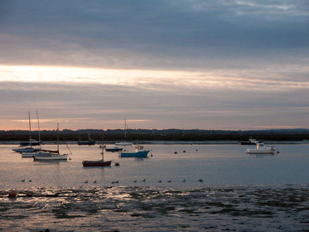 istock sun set sky dramatic clouds sea front beach harbor marina boats moored landscape 877184082